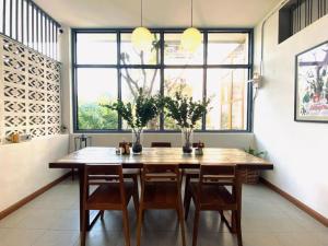 a dining room table with chairs and a large window at Baan Chiang Bed Lampang in Ban Nam Thong