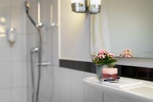 a bathroom with a sink and a vase of flowers on a counter at Hotel Kronprinz Hamburg Hauptbahnhof in Hamburg +23 photos