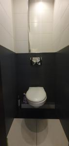 a bathroom with a white toilet in a black wall at Apartament Gdynia Kazart.Pl in Gdynia