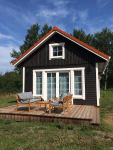 una pequeña casa con una terraza con un banco y una mesa en Domki na piasku, en Smołdziński Las