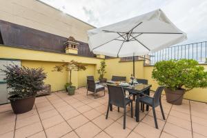 a table and chairs with an umbrella on a patio at DiVino Holiday Apartments in Alba