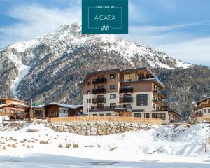 a building in front of a snow covered mountain at Lakeside by A CASA in Sölden