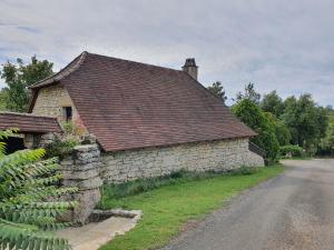 a stone house with a stone wall next to a road at Gîtes sur Le Causse de St CHELS, charme sport et détente in Saint-Chels