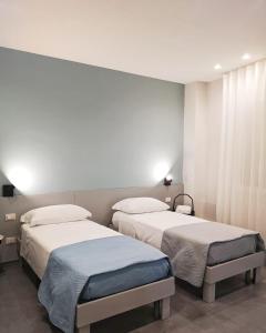 twee bedden in een kamer met witte muren bij Agathè Luxury Bed and Breakfast in Marina di Schiavonea