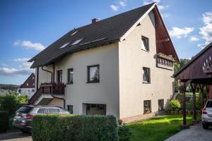 une grande maison blanche avec un toit noir dans l'établissement Ferienwohnung in ruhiger Waldrandlage, à Bärenstein