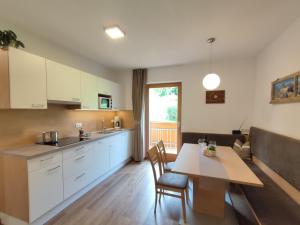 eine Küche mit weißen Schränken sowie einem Tisch und Stühlen in der Unterkunft Pramstaller Apartments in St. Lorenzen