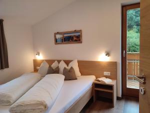 um quarto com uma cama grande e lençóis brancos em Pramstaller Apartments em San Lorenzo di Sebato