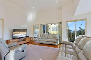 a living room with two couches and a flat screen tv at Family Tides Holiday Home in Apollo Bay
