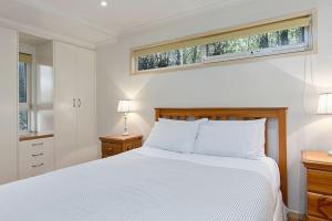 a white bedroom with a large bed and a window at Family Tides Holiday Home in Apollo Bay