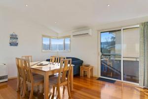 a dining room with a table and chairs and a couch at Family Tides Holiday Home in Apollo Bay