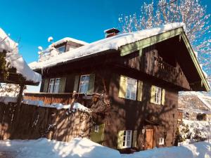 Schatzl Hütte في باد تولز: منزل مغطى بالثلج مع سياج