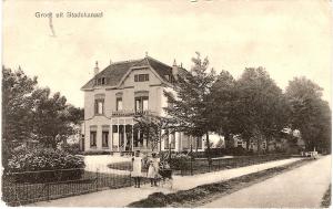 una vieja foto de una casa con dos personas de pie delante de ella en B&B Villa de Beuk, en Stadskanaal