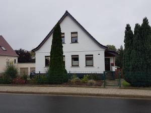 Una casa blanca con un árbol delante. en Ferienwohnung Schmenkel, en Angermünde