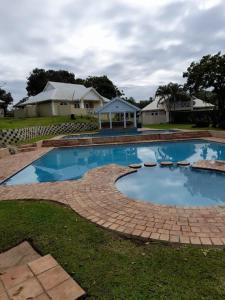 a large swimming pool in a yard with a house at 19 MONTEGO BAY CARIBBEAN Estate in Port Edward