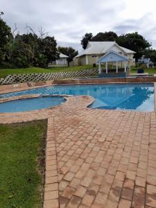 a swimming pool with a house in the background at 19 MONTEGO BAY CARIBBEAN Estate in Port Edward