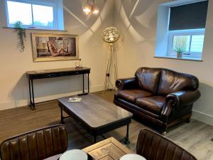 a living room with a leather couch and a table at Oddfellows Hall in Thetford