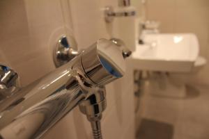 a shower head in a bathroom with a sink at Stasjonen Hotel Lillehammer in Lillehammer +41 photos