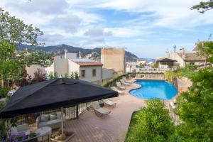 un patio al aire libre con piscina y sombrilla en Boutique Hotel Casa Granados en Tossa de Mar