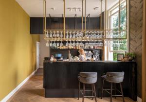 a bar with two stools in a room with yellow walls at Hotel Flora Batava in Breukelen