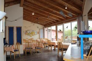 uma sala de jantar com mesas, cadeiras e janelas em Hotel Windfelder em Stegaurach