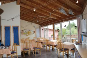 uma sala de jantar com mesas, cadeiras e janelas em Hotel Windfelder em Stegaurach