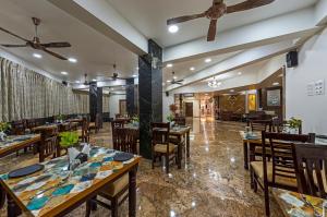 uma sala de jantar com mesas e cadeiras de madeira em Hotel Blooming Soul em Kolhapur