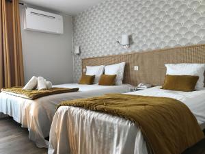 twee bedden in een hotelkamer met twee bij Hôtel Le Glacier in Villeneuve-sur-Lot