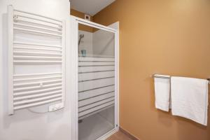 a bathroom with a glass shower stall and white towels at Appart'City Niort in Niort