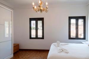 1 dormitorio con 1 cama con lámpara de araña y 2 ventanas en ELHIERRO BED&URBAN I, en Valverde
