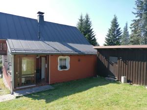 une petite maison rouge avec un toit noir dans l'établissement Fichtelfeeling, à Fichtelberg