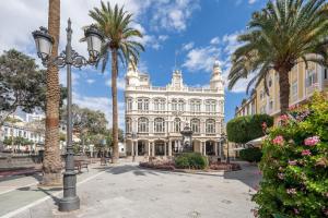 ein großes weißes Gebäude mit Palmen und einem Straßenlicht in der Unterkunft Boutique Hotel Cordial La Peregrina in Las Palmas de Gran Canaria + 32 Fotos