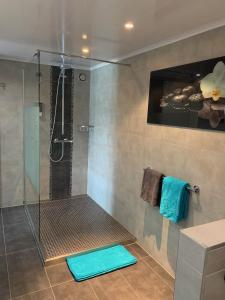 La salle de bains est pourvue d'une douche avec des tapis bleus. dans l'établissement Country house Au Ballet des Hirondelles, à Herve