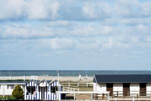 a group of buildings on a beach with the ocean at Le LUXE & votre VUE MER à Ouistreham Riva Bella in Ouistreham