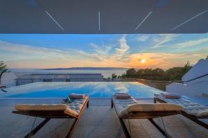 einen Pool mit Blick auf den Sonnenuntergang in der Unterkunft Luxury Villa Hedone in Baška Voda