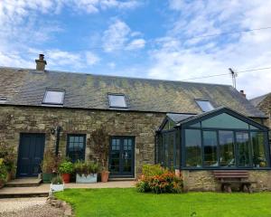 a stone house with a conservatory on the front of it at Trossachs Barn & Cabin in Port of Menteith