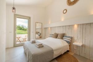 ein weißes Schlafzimmer mit einem großen Bett und einem Fenster in der Unterkunft Casa Luce in Torre di Palme