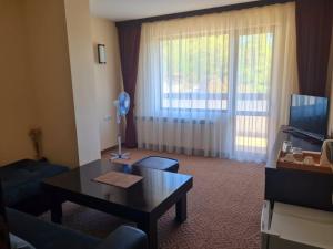 a living room with a table and a large window at Family Hotel Bela in Tryavna