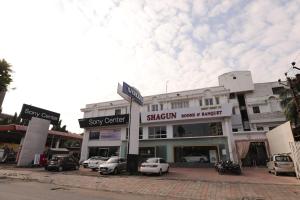 un edificio con coches estacionados en un estacionamiento en Hotel Shagun Rooms & Banquet, Surat, en Surat