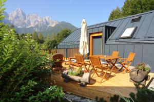 a deck with a table and chairs and a house at Vila Edelweiss Rooms&App Kranjska Gora in Kranjska Gora