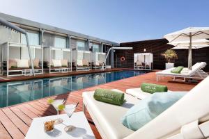 une piscine avec des chaises longues blanches et un hôtel dans l'établissement The Level at Melia Barcelona Sky, à Barcelone