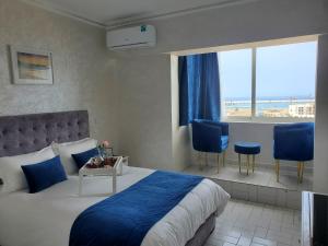 a bedroom with a bed and two chairs and a window at Panoramic Sea View Apartment 1 Min Walk to Beach in Tangier