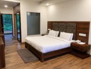 Hotel Chail Residency في تشايل: غرفة نوم بسرير كبير مع شراشف بيضاء