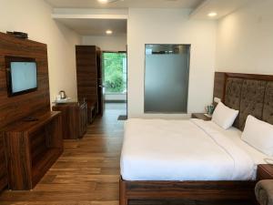a bedroom with a large white bed and a television at Hotel Chail Residency in Chail