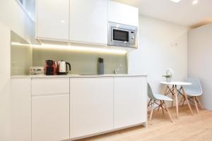 a white kitchen with white cabinets and a table at Earls Court East Serviced Apartments by StayPrime in London