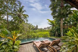 a patio area with chairs, tables, and umbrellas at Madani Antique Villas in Ubud
