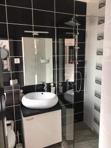 a bathroom with a sink and a glass shower at Cuki Apartmanok in Dombóvár