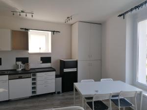 kuchnia z białym stołem i białymi szafkami w obiekcie Cuki Apartmanok w mieście Dombóvár +12 zdjęć
