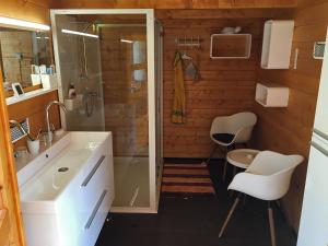 a bathroom with a shower and a sink and two chairs at Lookout Resort tiny houses in Rovte