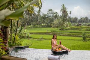 
a woman sitting on a boat in the middle of a lake at Madani Antique Villas in Ubud
