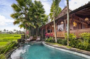 a beach scene with a pool and a house at Madani Antique Villas in Ubud